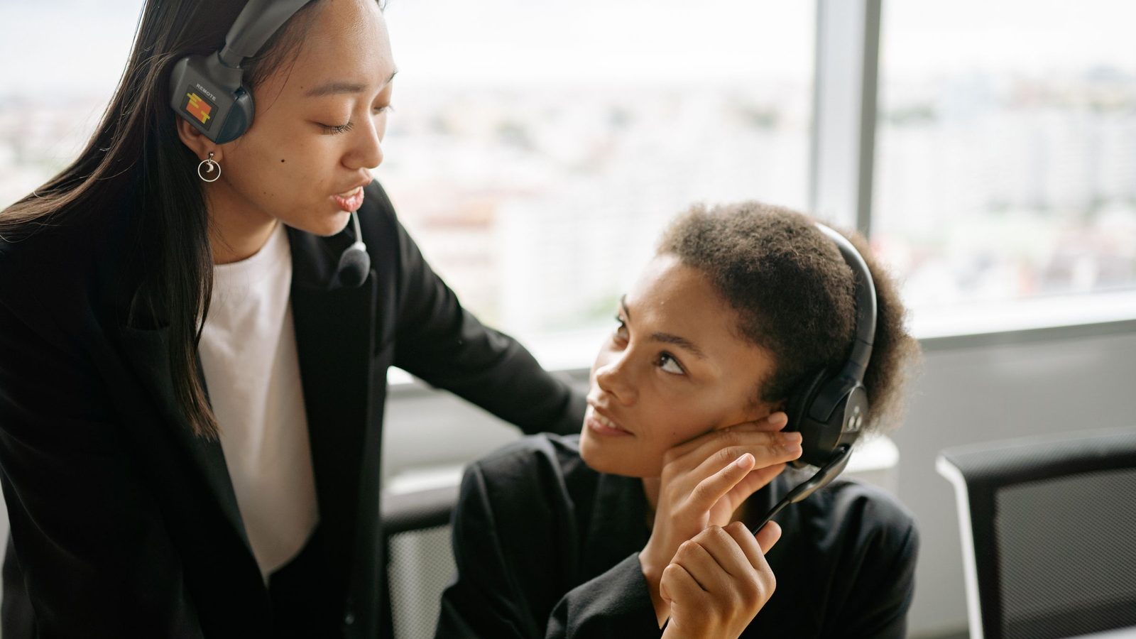 Two call center agents discussing strategies with headsets in a modern office setting