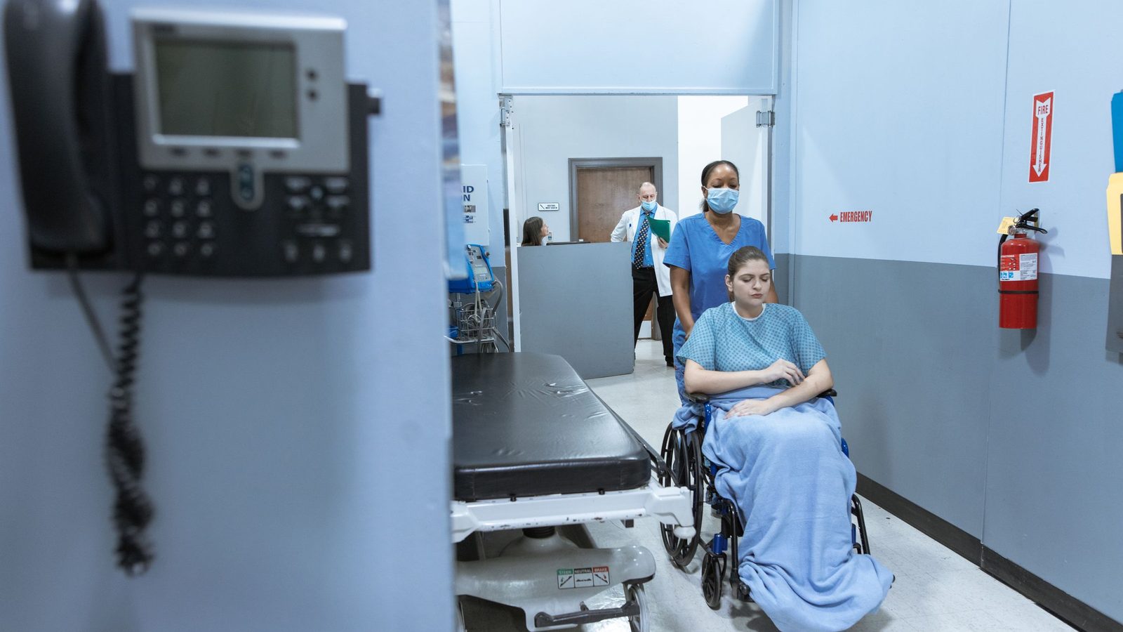 Healthcare support staff and a service manager walking through a modern hospital corridor