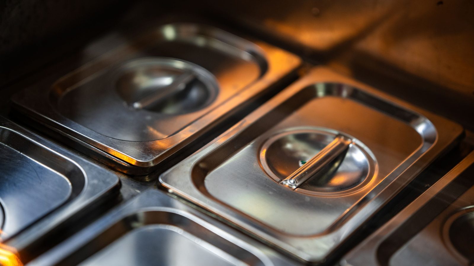 Stacks of shiny stainless steel food containers in a professional kitchen setting