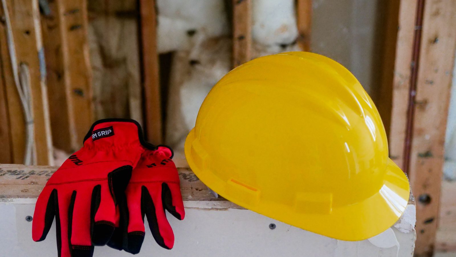 Close-up of a yellow hard hat and protective gloves on a work site