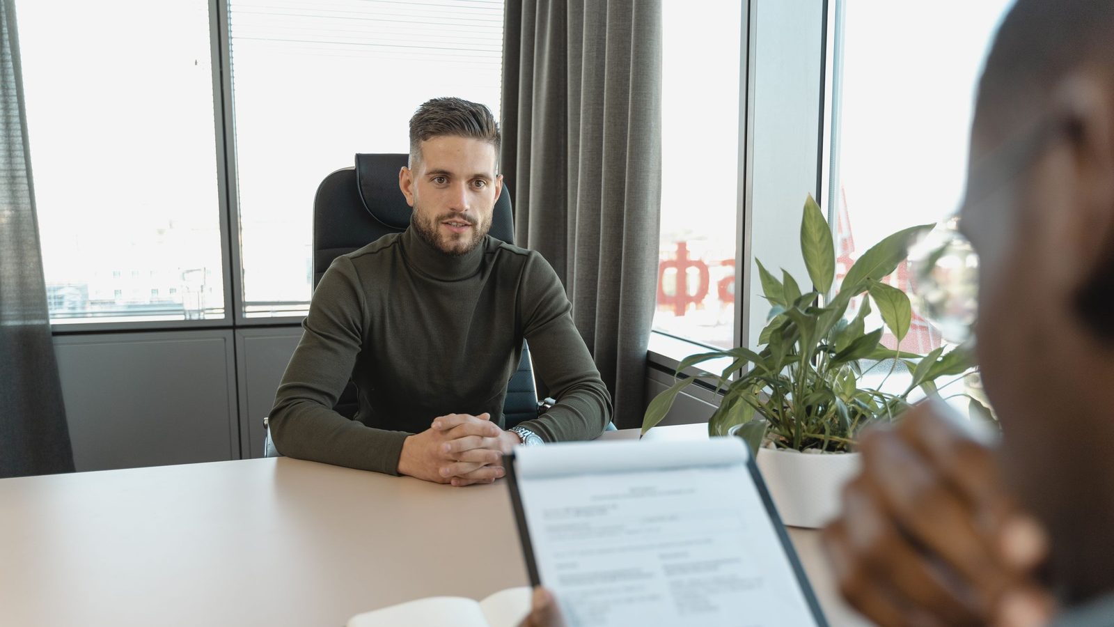 Professional man in turtleneck at office desk during an interview