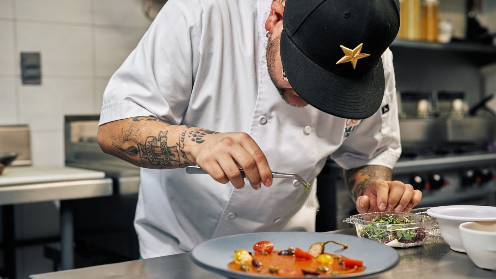 Close-up of a chef in a professional kitchen garnishing a gourmet dish with precision