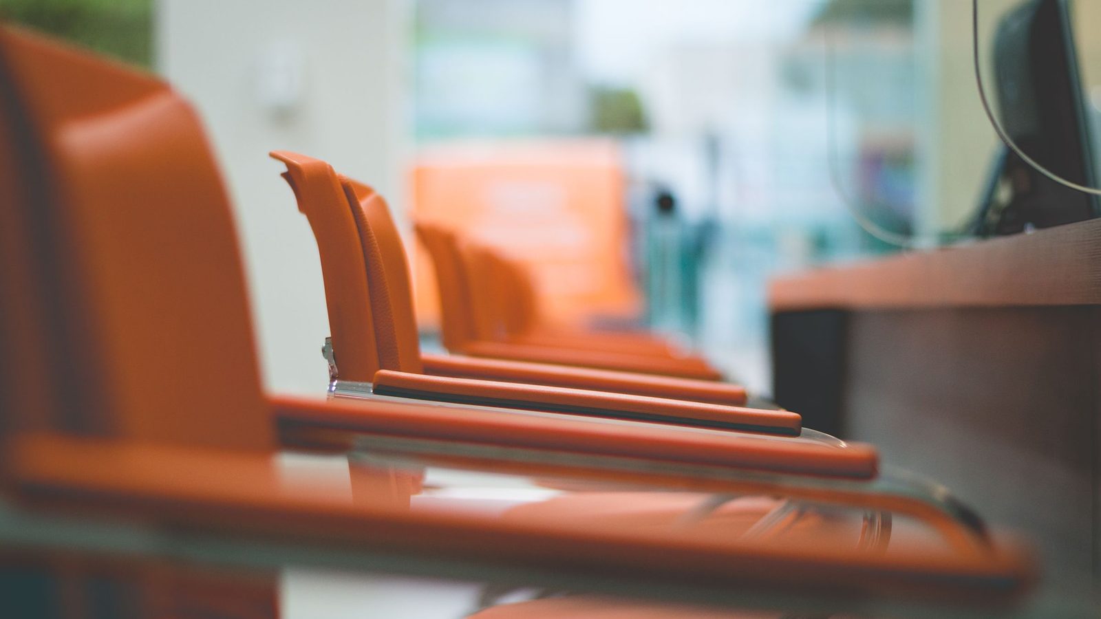 Close-up of sleek orange office chairs in a waiting area with focus on design