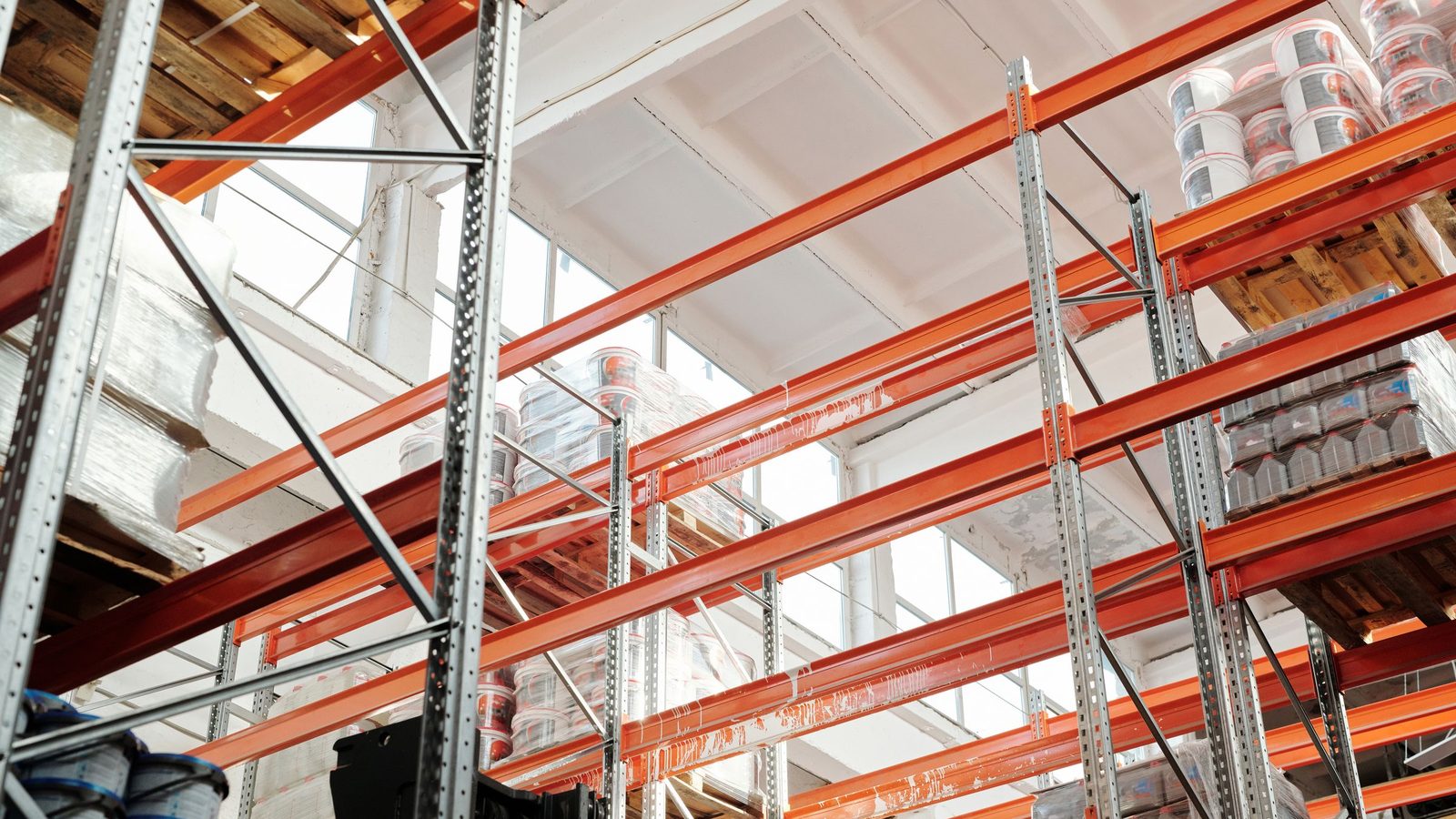 Bright warehouse interior with orange metal shelving units and stored goods