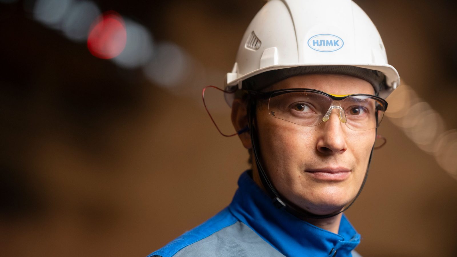 Confident male engineer wearing safety helmet and goggles in industrial setting